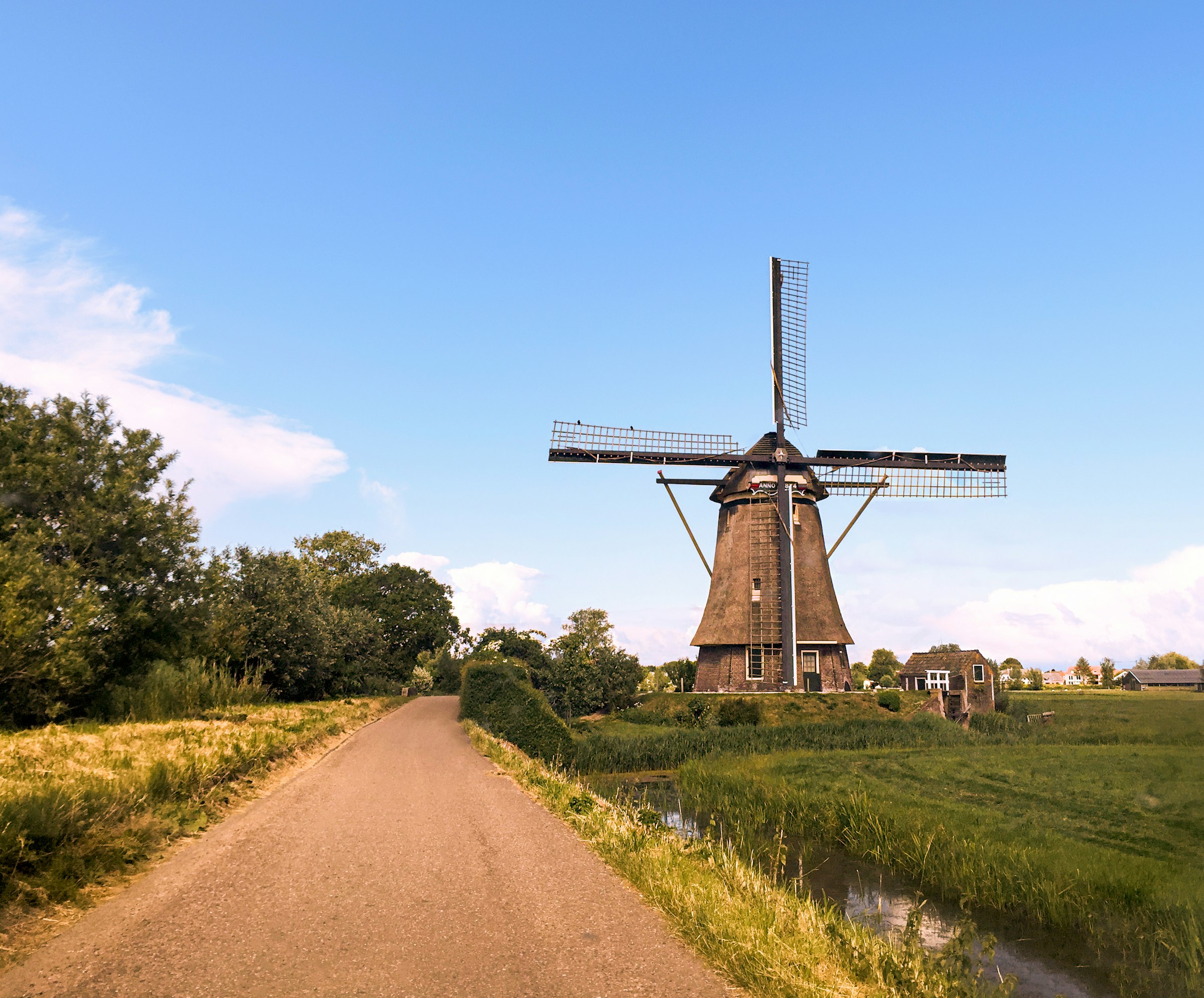 Dutch windmill on green grass under a bright blue sky